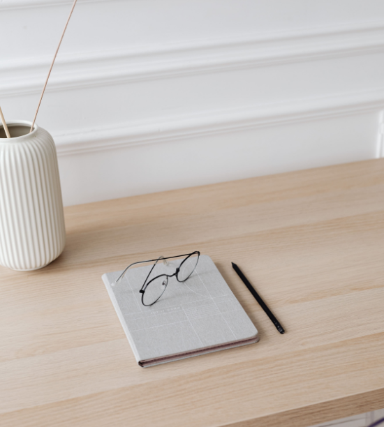 Un cahier et des lunettes posés sur un bureau